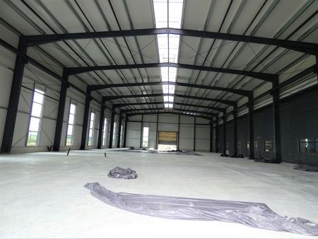 Großes Lagerhaus mit großen Fenstern, das viel Tageslicht hereinlässt und eine offene, geräumige Atmosphäre schafft.